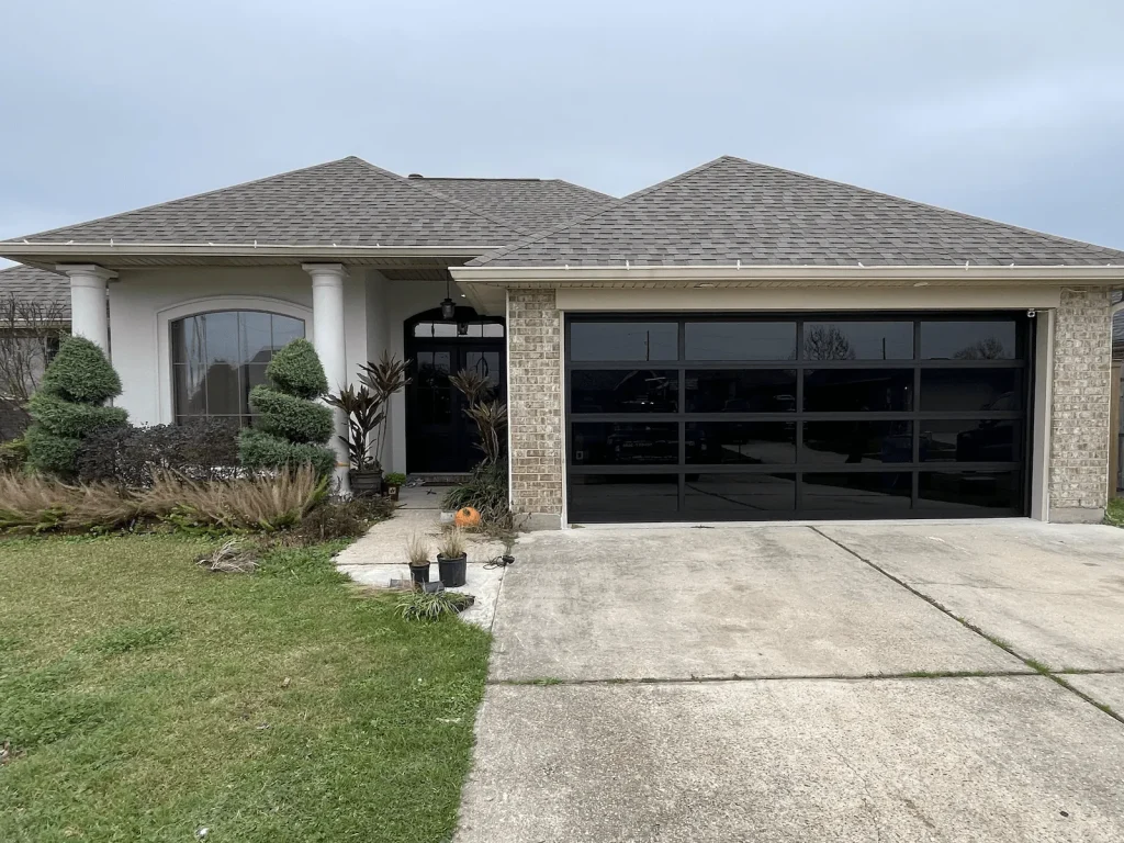 Modern full-view glass garage door installed on a brick home in Metairie, LA