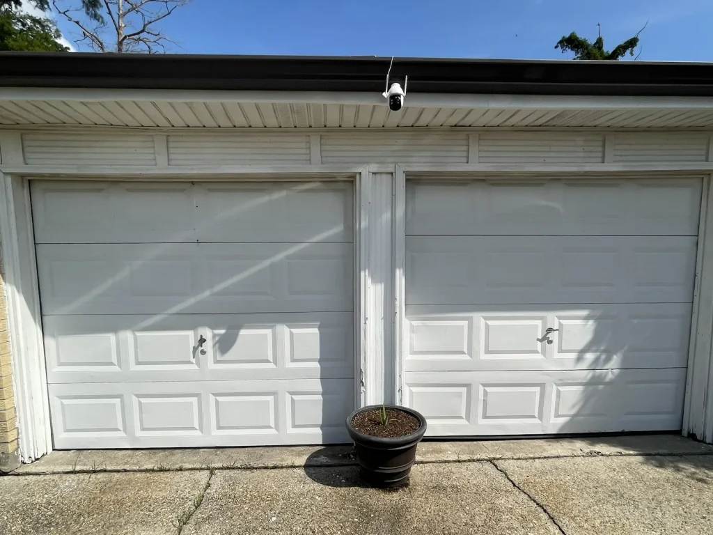 Aging white two-car garage door before replacement on a New Orleans area home