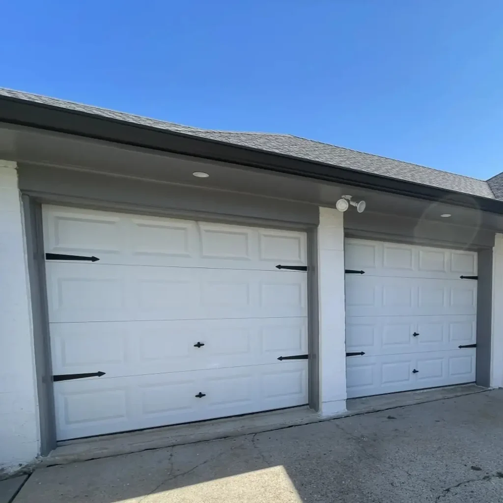 White carriage-style garage door with decorative hardware before replacement — New Orleans home