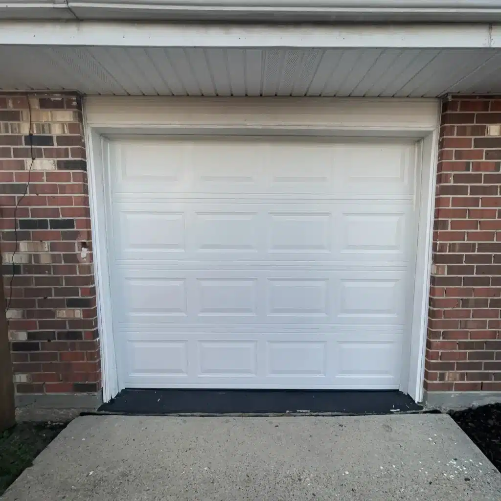 Replacement white raised-panel garage door installed on a brick home in Kenner, LA