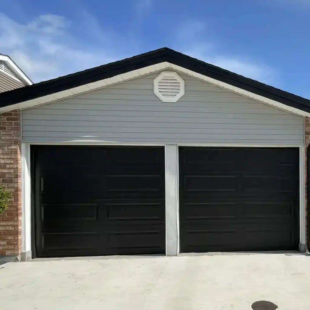 New dark charcoal two-car garage door installed on a brick home in Metairie, LA