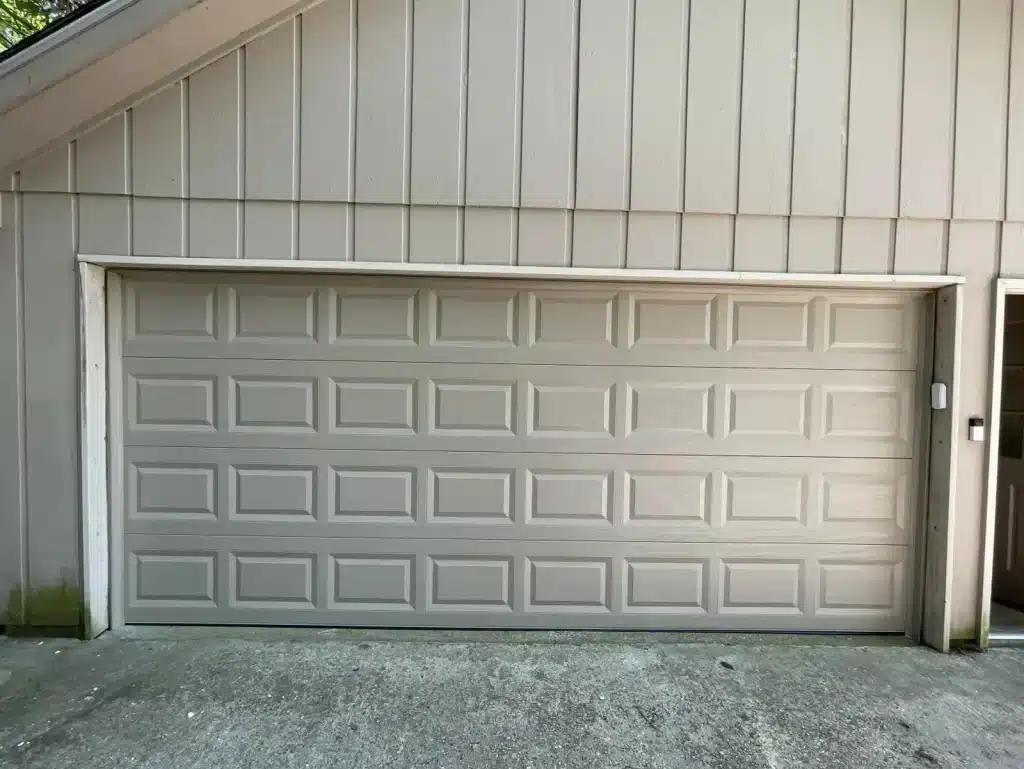 New tan raised-panel two-car garage door installed on a New Orleans area home