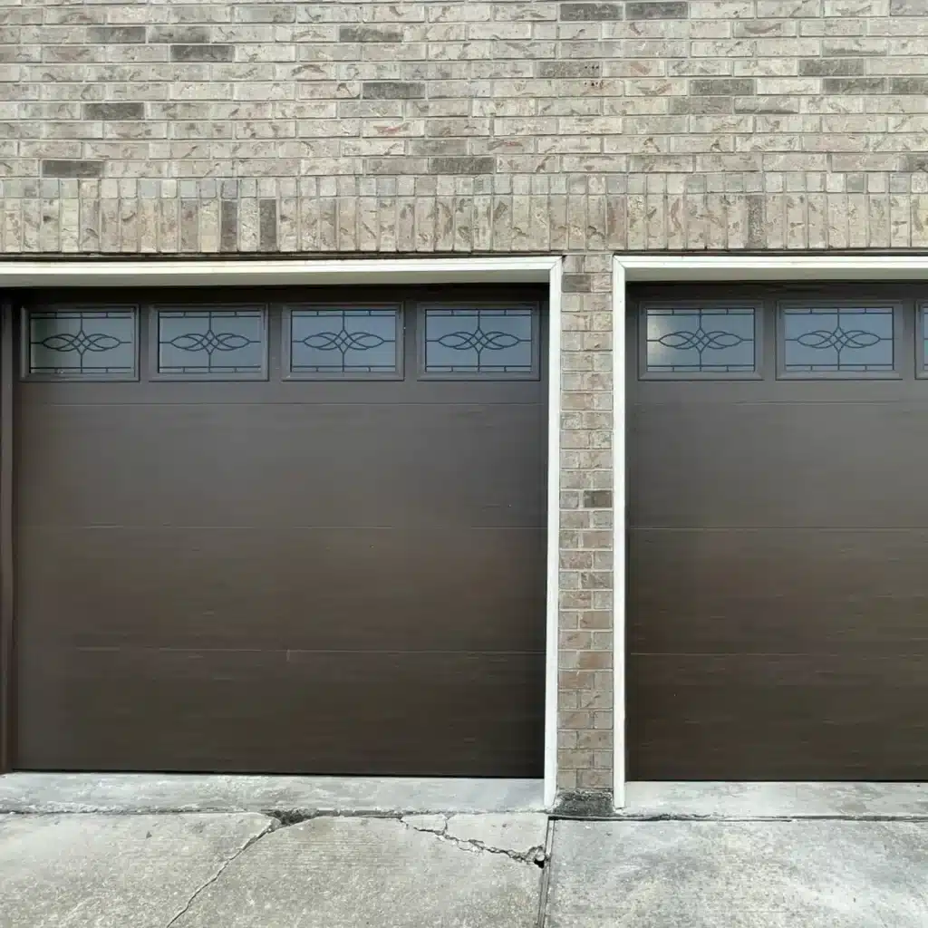 New dark brown garage door with decorative window inserts installed on a Metairie brick home