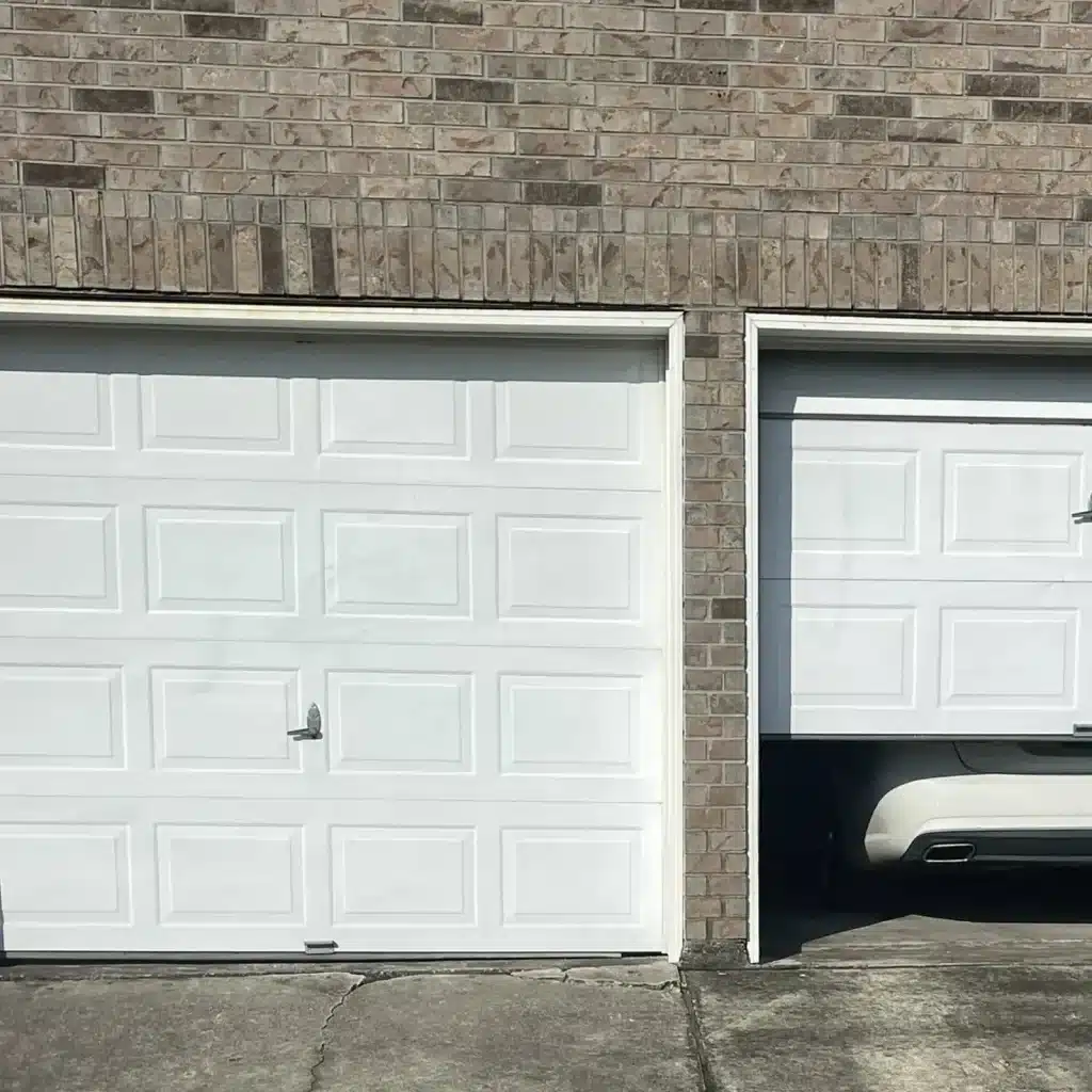 White raised-panel garage door on a Metairie brick home before replacement