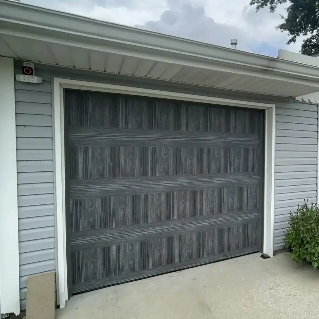 New charcoal wood-look single-car garage door installed on a home in Gretna, LA