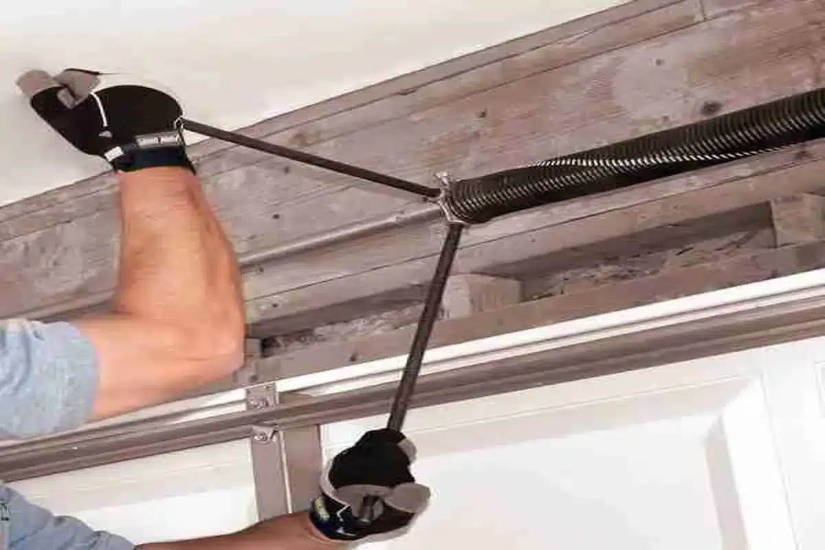 Garage door technician using winding bars to adjust torsion spring
