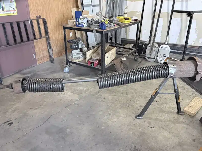 Rolling steel door spring assembly staged for replacement at a New Orleans commercial job site