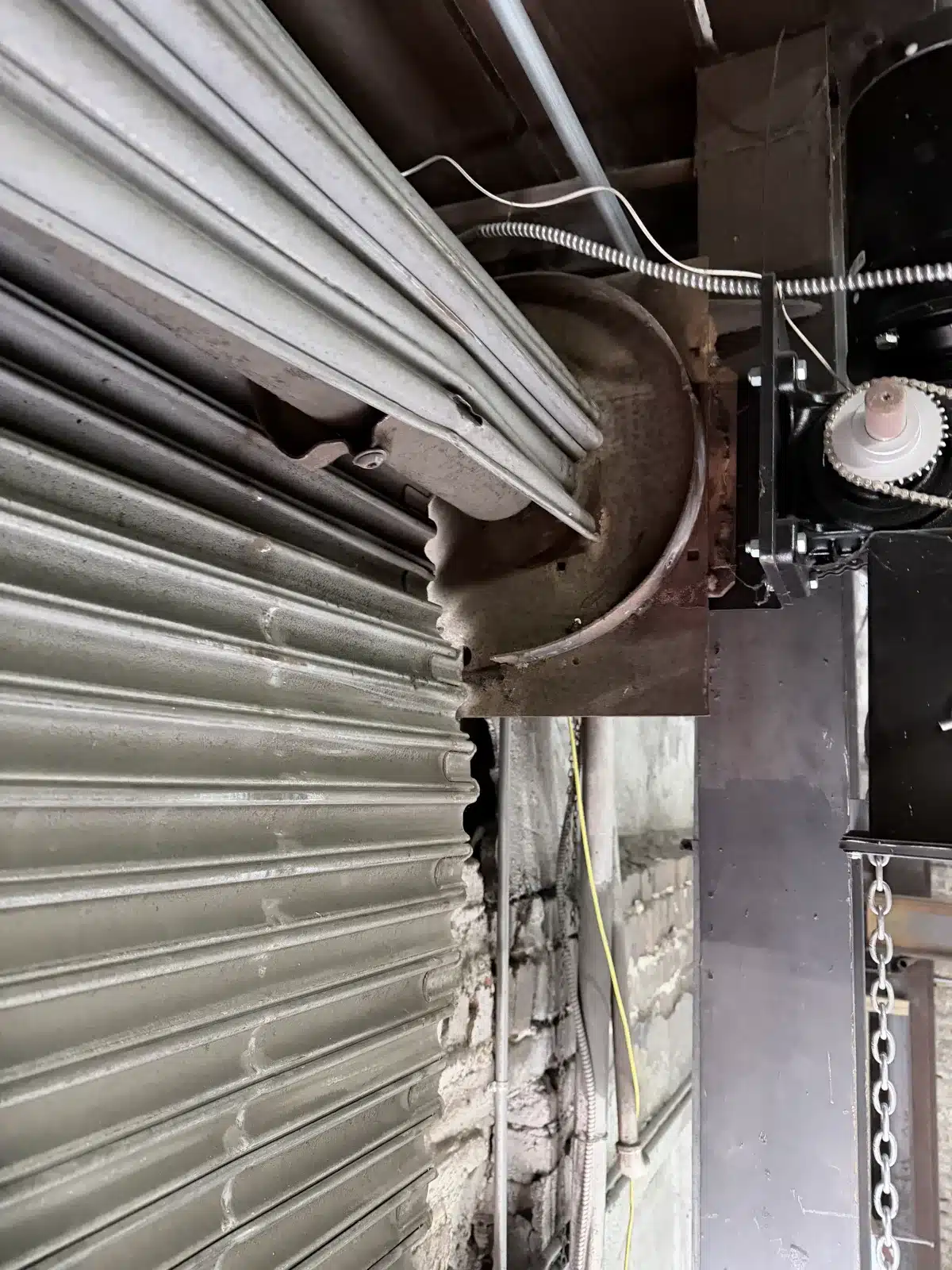Commercial rolling steel door with barrel end cap visible during spring repair in New Orleans Louisiana