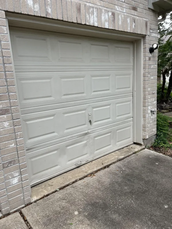 Damaged garage door panel from vehicle impact in New Orleans
